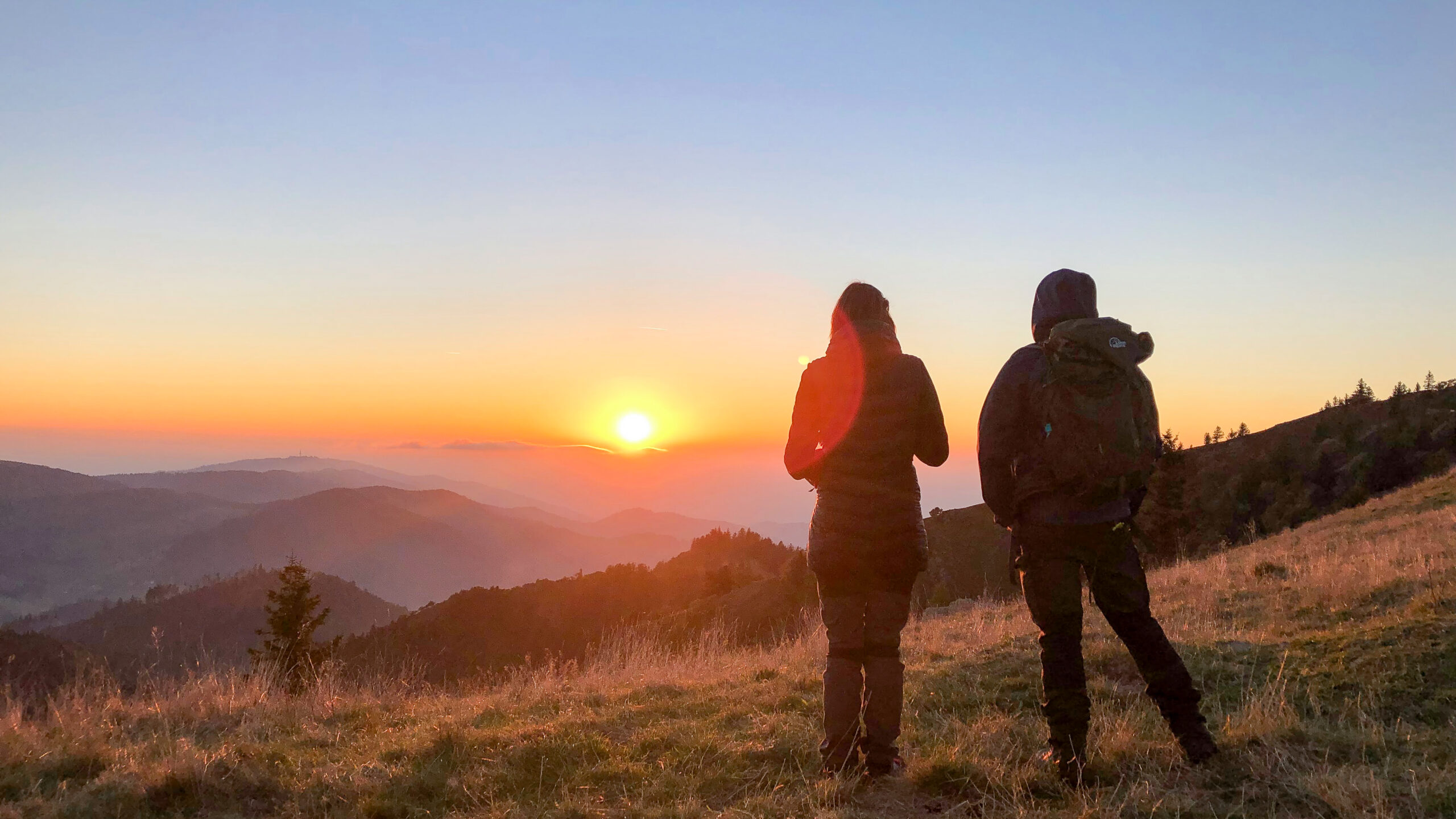 Wanderer genießen den Sonnenuntergang auf dem Belchen im Schwarzwald